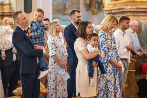 Rodzice niosący dziecko przed wejściem do kościoła na mszę świętą