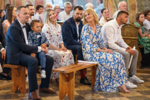 Rodzice i chrzestni zgromadzeni wokół chrzcielnicy podczas ceremonii, reportaż z sakramentu Chrztu Świętego
