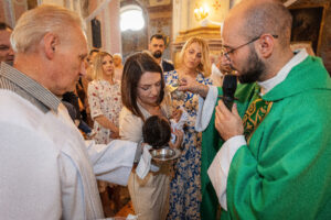 ksiadz polewa glowke dziecka na chrzcie w kobylce