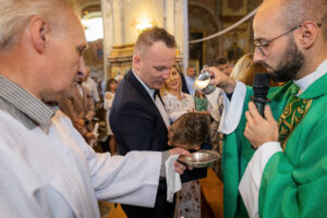 Polewanie główki dziecka wodą święconą nad chrzcielnicą, kluczowy moment sakramentu chrztu, fotograf na chrzest