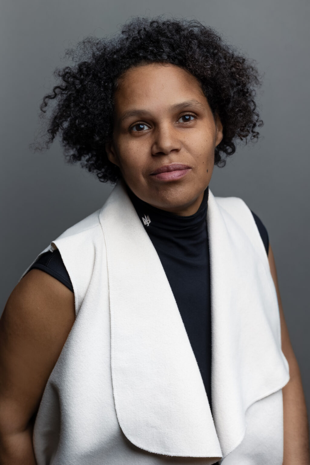 Portret wizerunkowy kobiety z kręconymi włosami w eleganckiej białej kamizelce, fotografia brandingowa.
